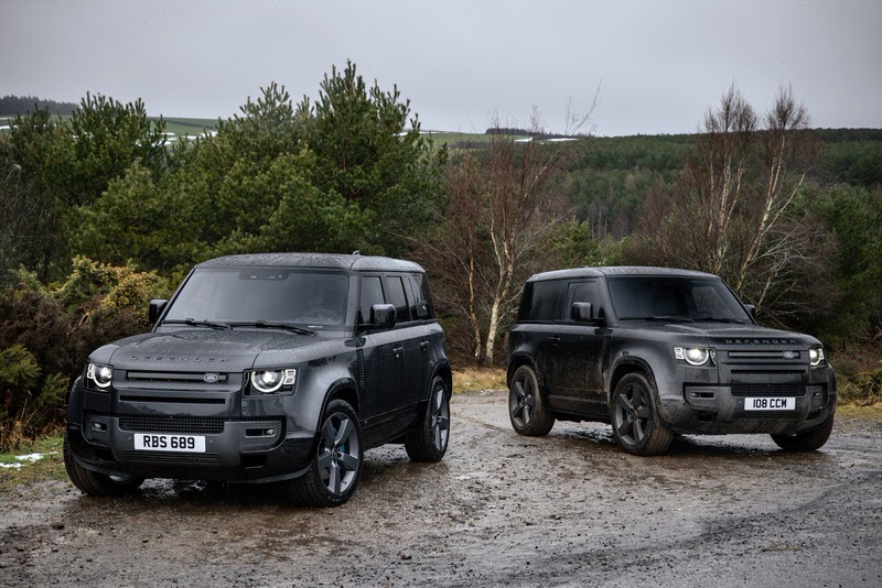 Two V8 Range Rover Defender SUVs in the mountains on a wet dirt road