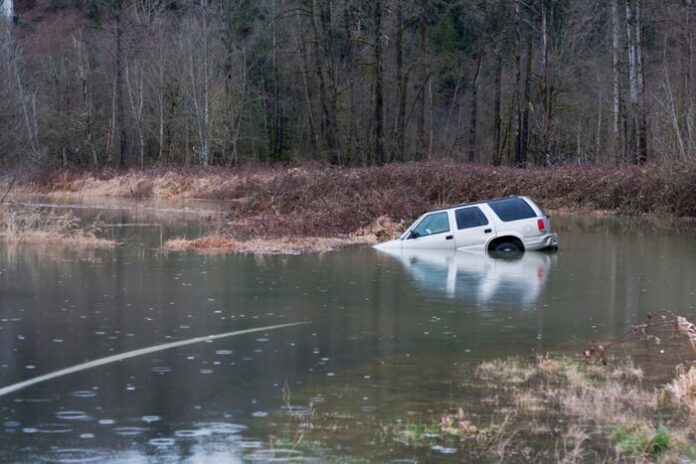 White SUV partially submerged in a river