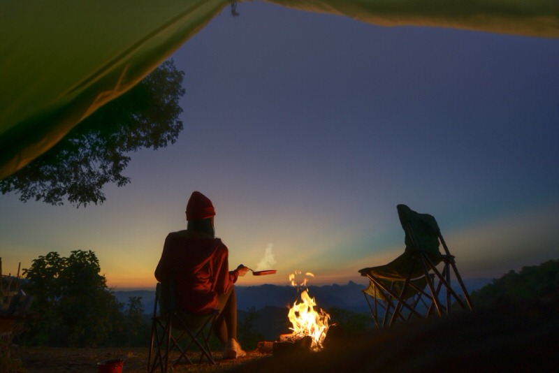 Person sitting next to a campfire