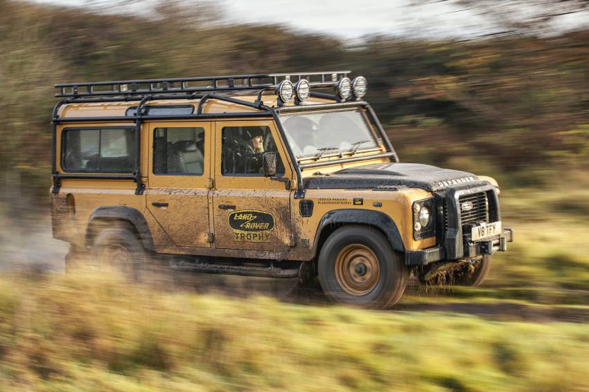 yellow land rover defender speeding down a dirt road