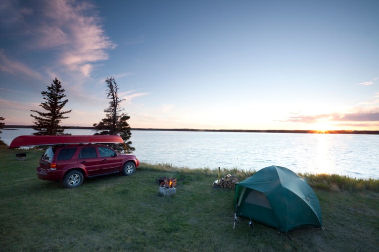 SUV next to a tent at a lake