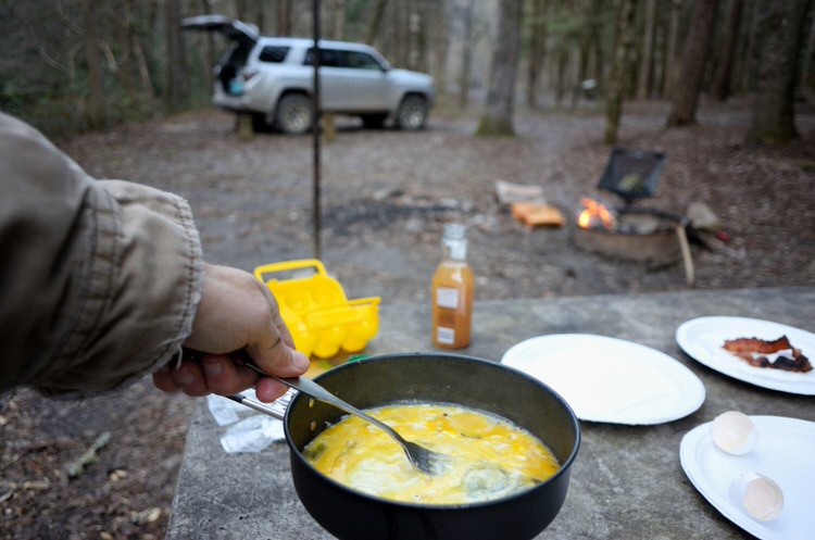 eggs cooking in cast iron pan with SUV in the background