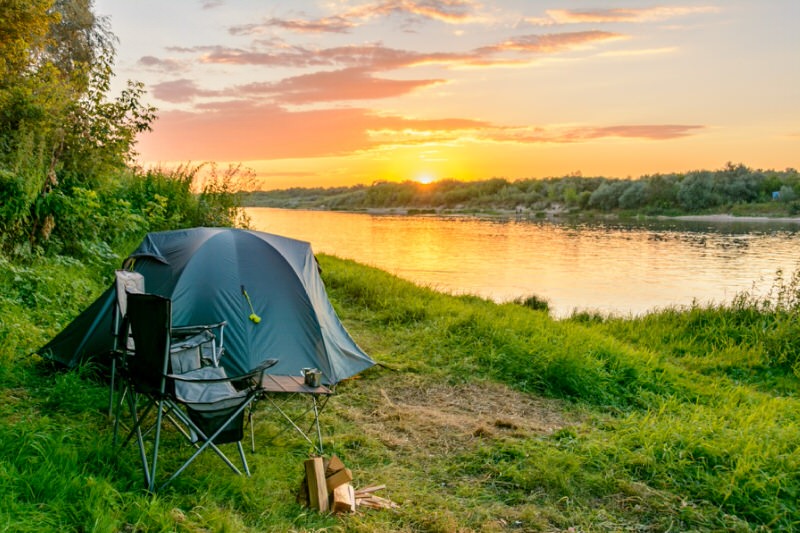 Ground camping tent set up near a pond at sunset
