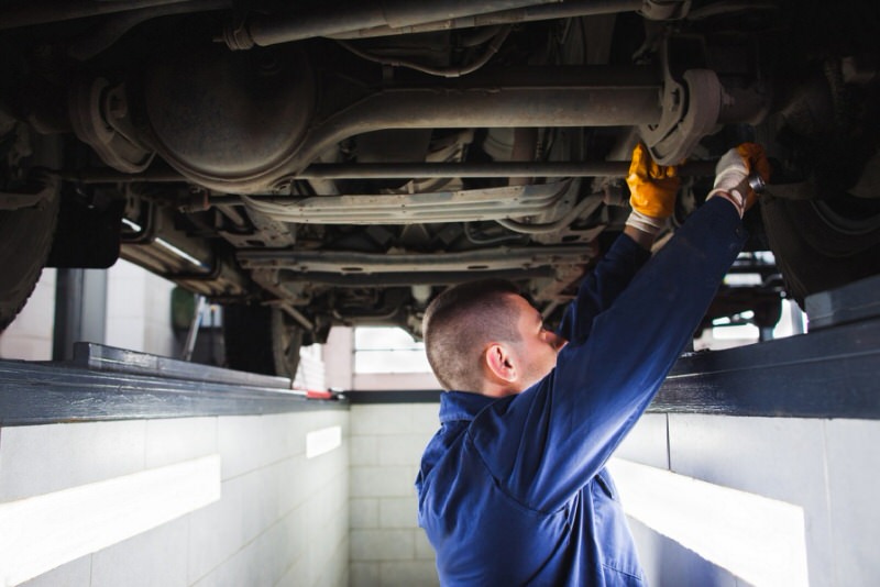 man working of the underside of an SUV