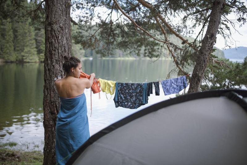 young woman using a clothes line to dry clothing items to Stay Clean When Out Camping