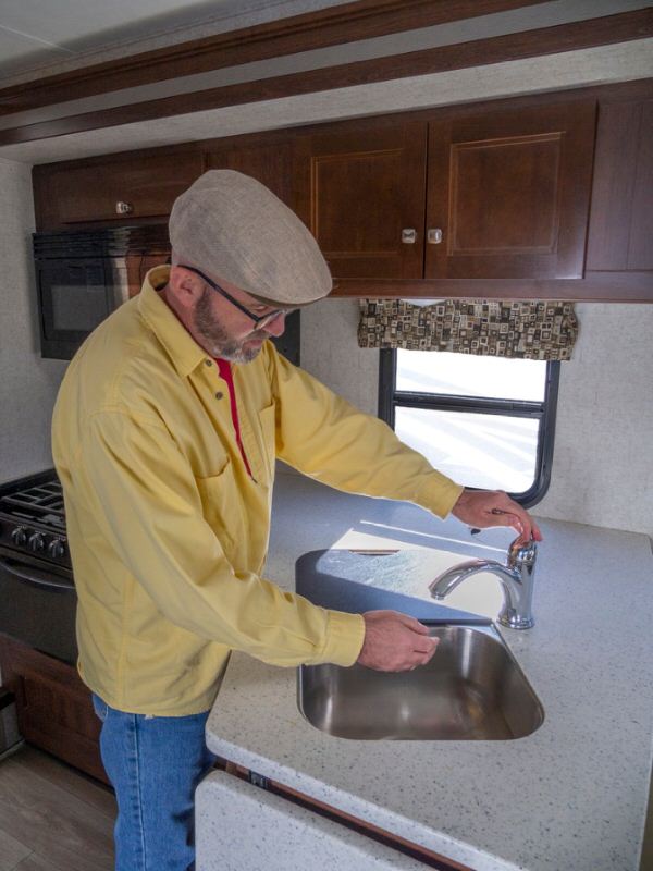 Man Flushing a camper sink to sanitize the water system