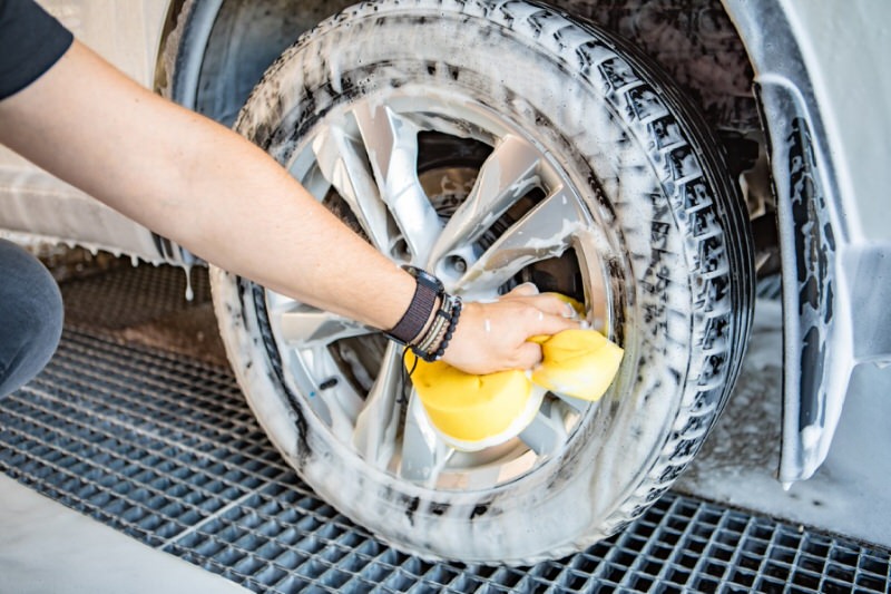 person cleaning a tire with a sponge