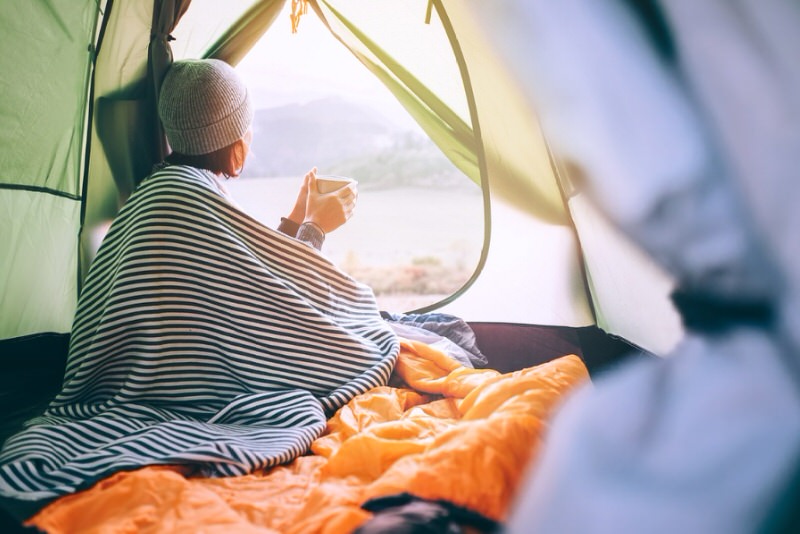 woman enjoying coffee in the opening of her tent