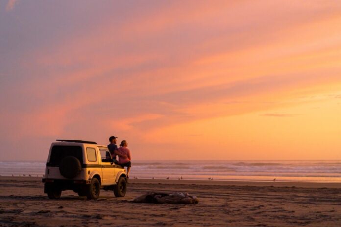 couple by a 4x4 looking at the ocean at sunset