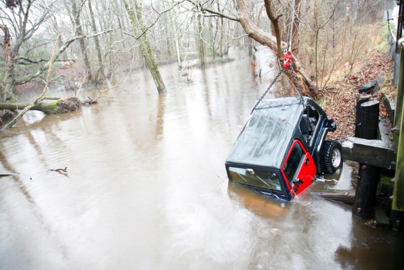 Jeep being lifted out of a river with and small wench