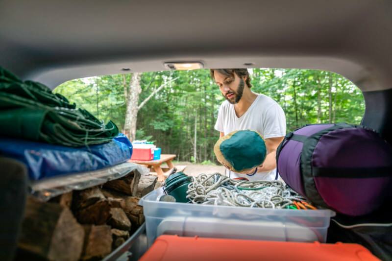 Man packing camping gear in a SUV trunk