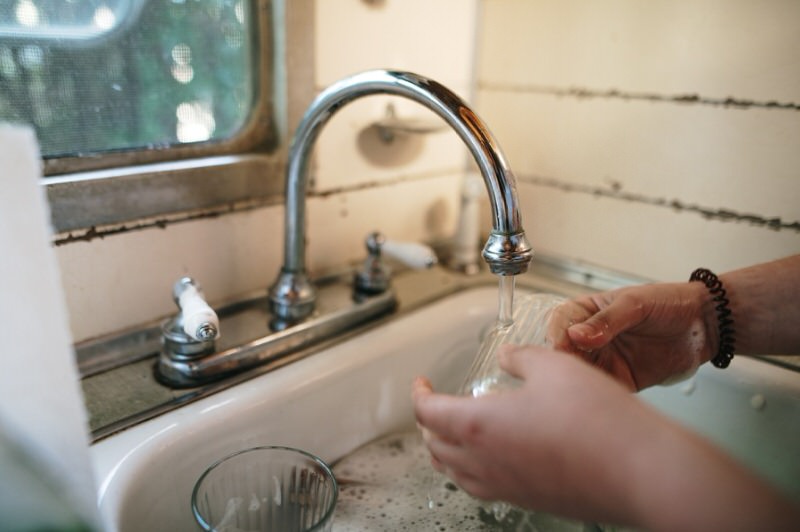 person washing dishes in a camper sink