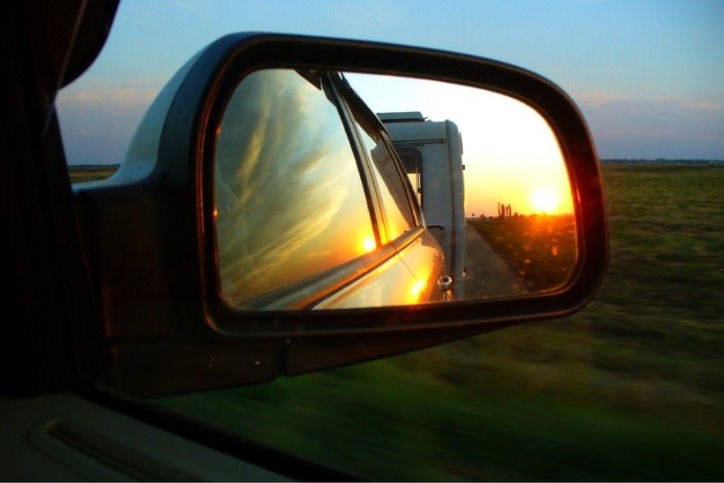 Trailer reflected in truck side mirror at sunset
