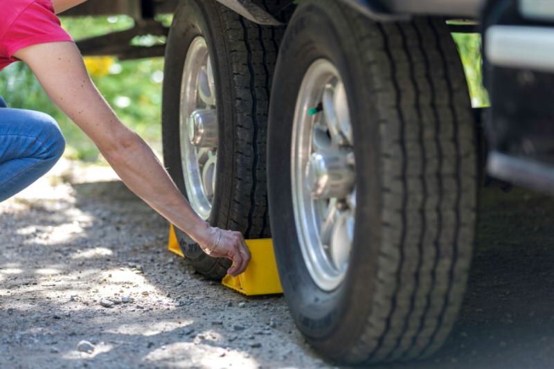 person placing wheel blocks around a tire