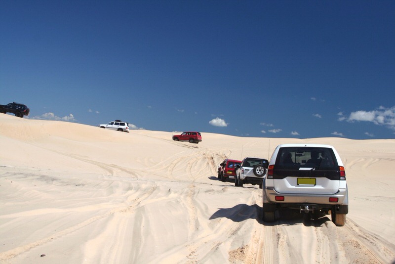Group of 4x4s driving up a sand dune