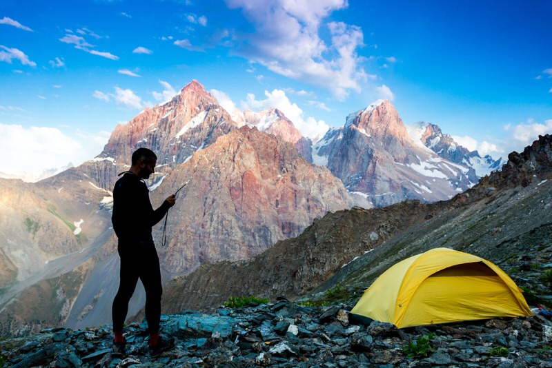 Man using a satellite phone in the mountains on a solo overlanding trip 