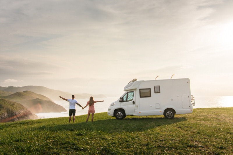people enjoying the sunset next to a camper