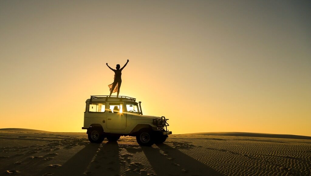Silhouette of a woman standing on SUV on a solo Overlanding trip