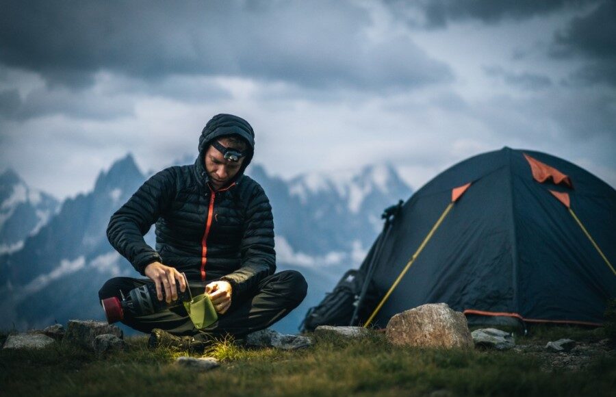 man pouring coffee while camping