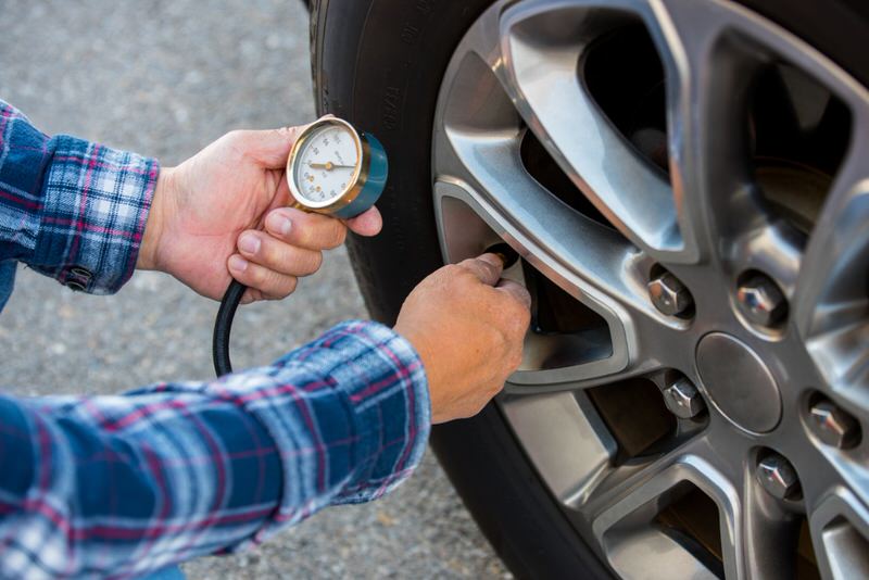 person checking tire pressure to save fuel