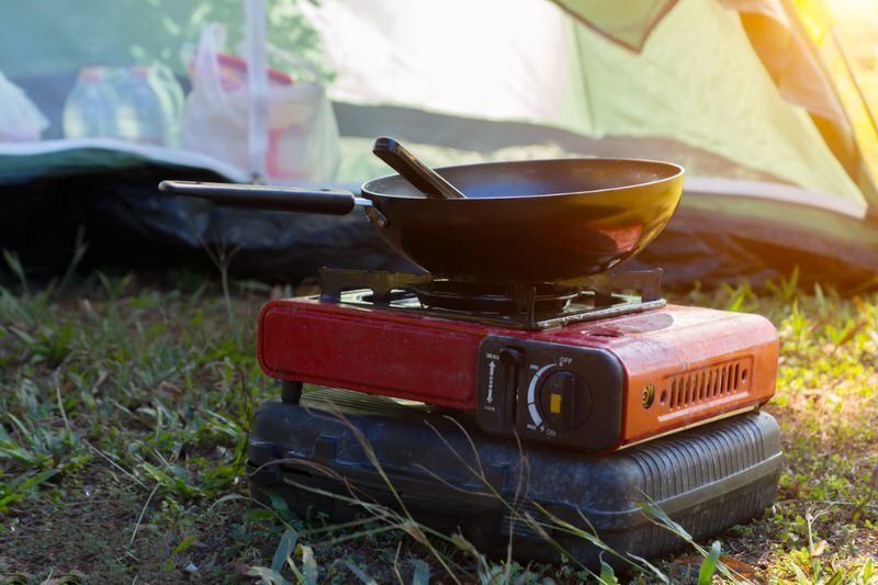 a pan on a camp stove with a tent in the background