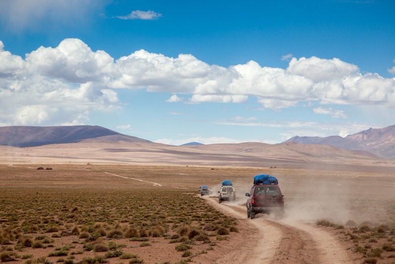 convoy of SUV on dirt road in a desert