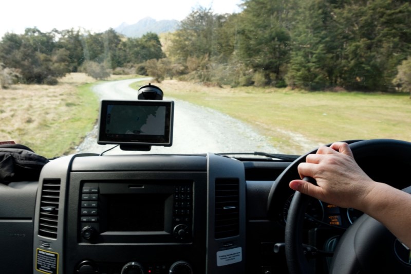 Car driving down a dirt road with a GPS on the Dash