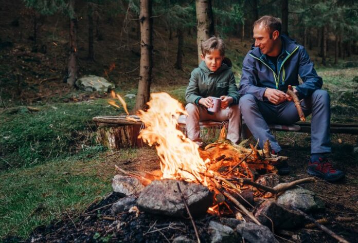 Man Overlanding With child sitting around a campfire