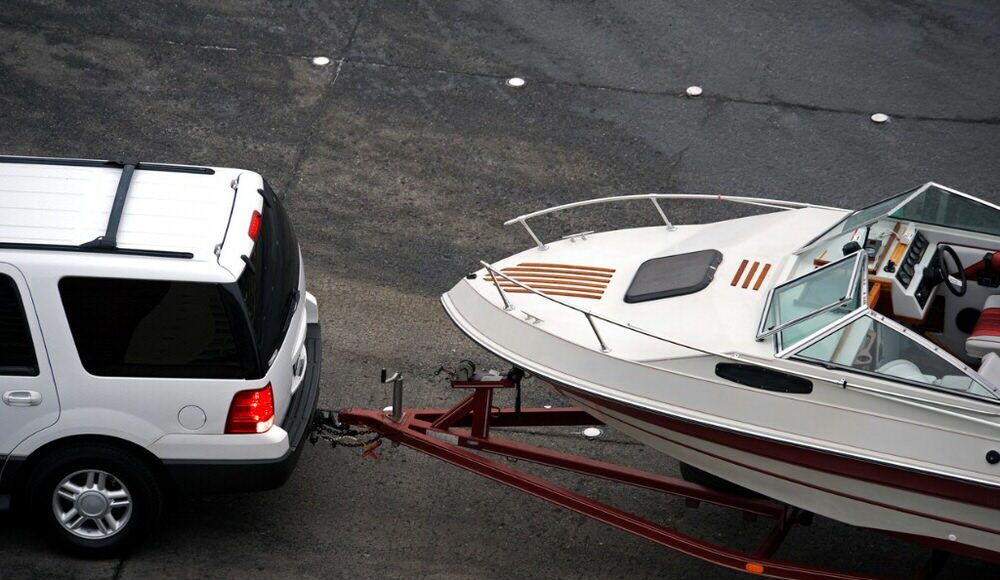 white SUV towing a boat off-road