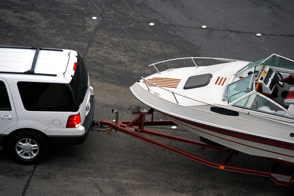 white SUV towing a boat off-road