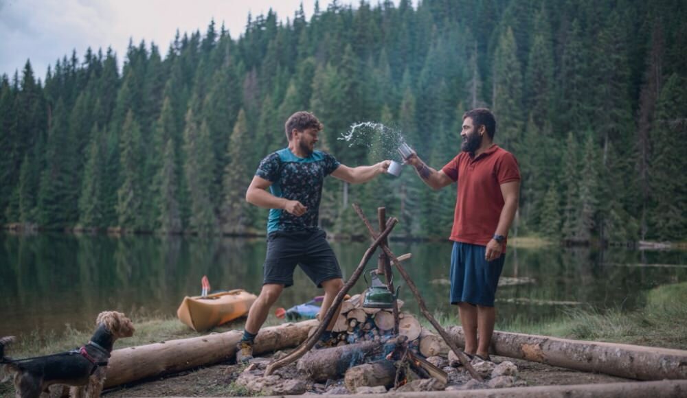 Two friends having a water fight in a campsite but a lake