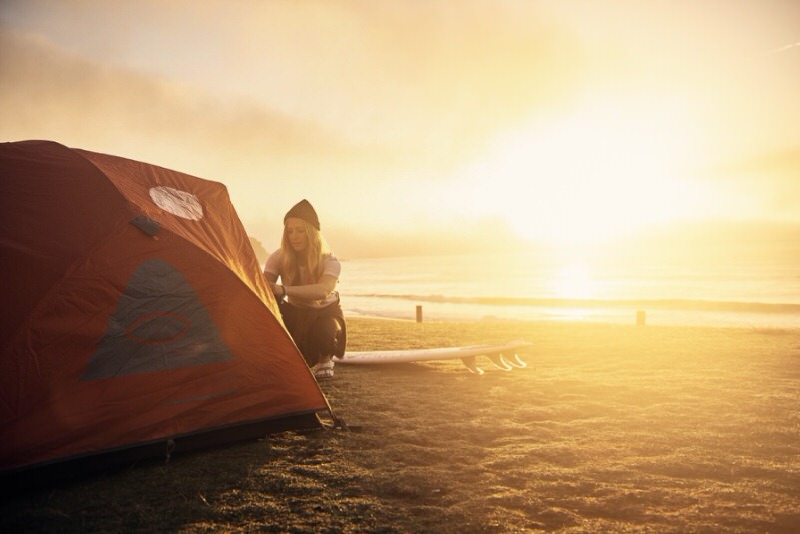 woman setting up tent for warm weather camping