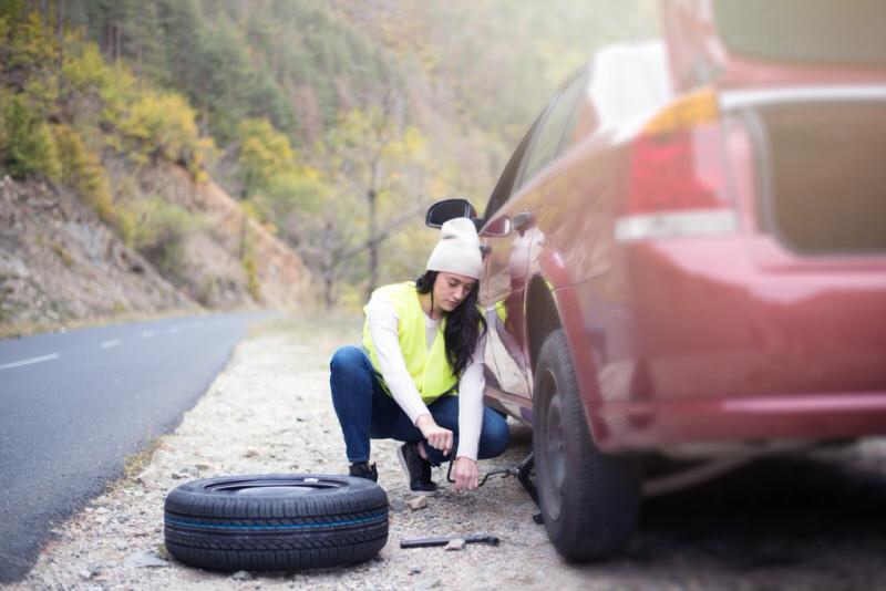 Woman changing a tire on the side of the road