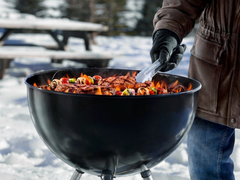 Person cooking on a grill in the snow