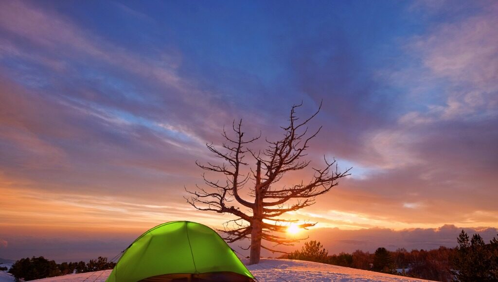 Camping in winter tent near a tree