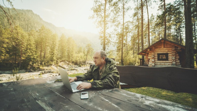 Man using a computer in the woods