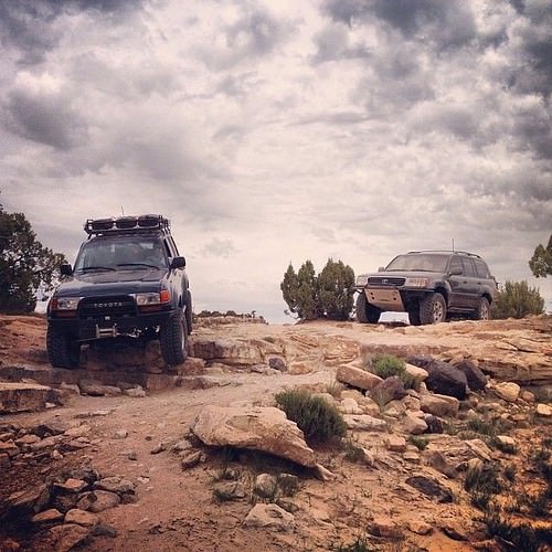 two 4x4 with rig armor driving over rocky terrain 