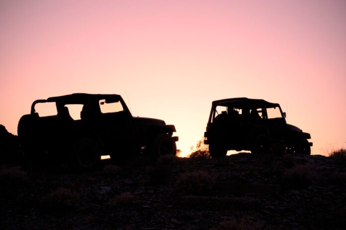 Two jeeps in silhouette off-roading