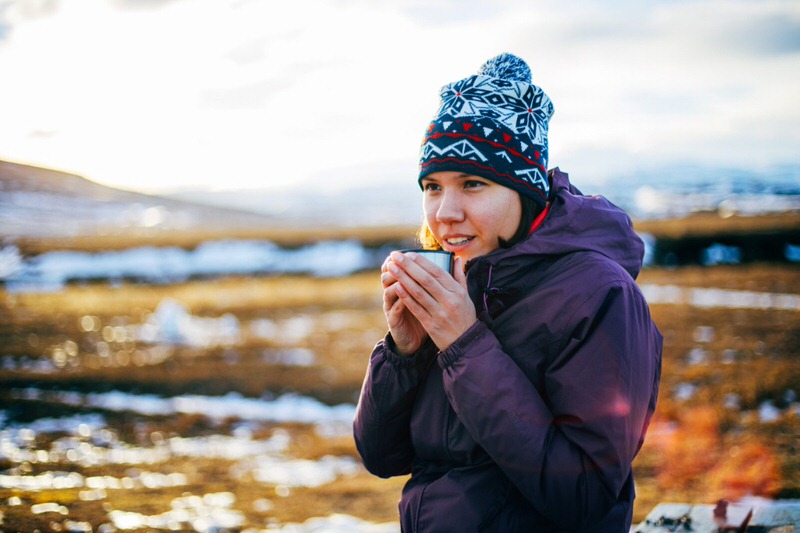 woman drinking tea to stay warm while cold weather camping