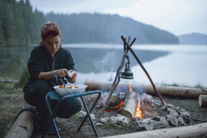 Young Woman Is Cooking Is Next To The Campfire