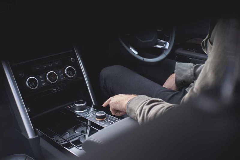 person pushing buttons on a car console