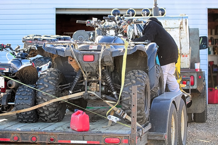 A young boy checking straps for quads on a trailer