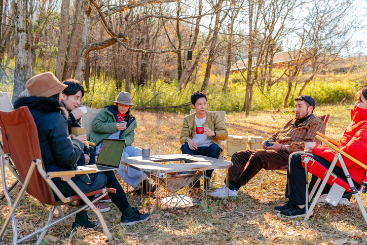 Group of friends enjoying drinking hot drink at camp site 