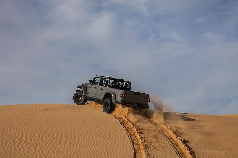 Jeep Gladiator driving up a sand dune 