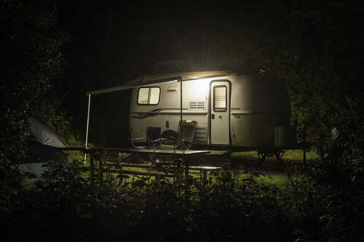Caravan trailer glowing in forest camp site night