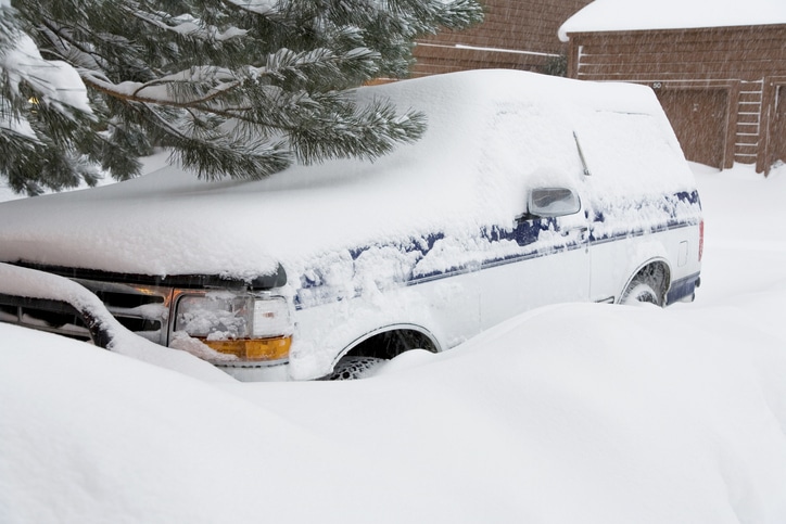 A large SUV vehicle partially buried in snow