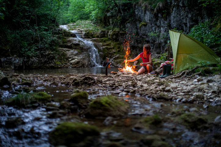 Adult Woman Camping Near a Creek in Forest.