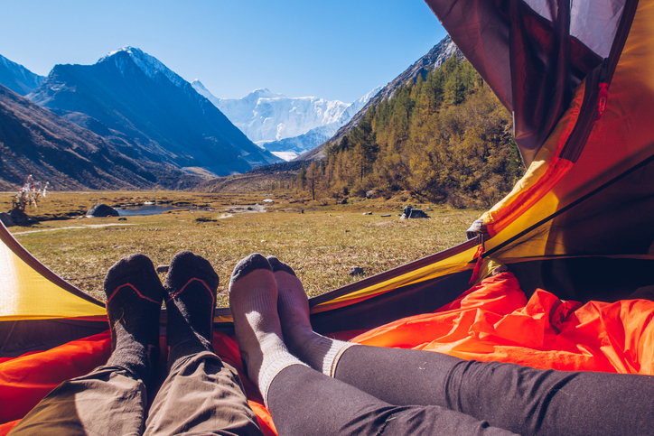 Two people lying in tent with a view of mountains