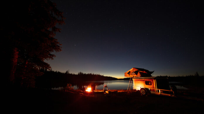 Camping next to lake with camp fire and tent.