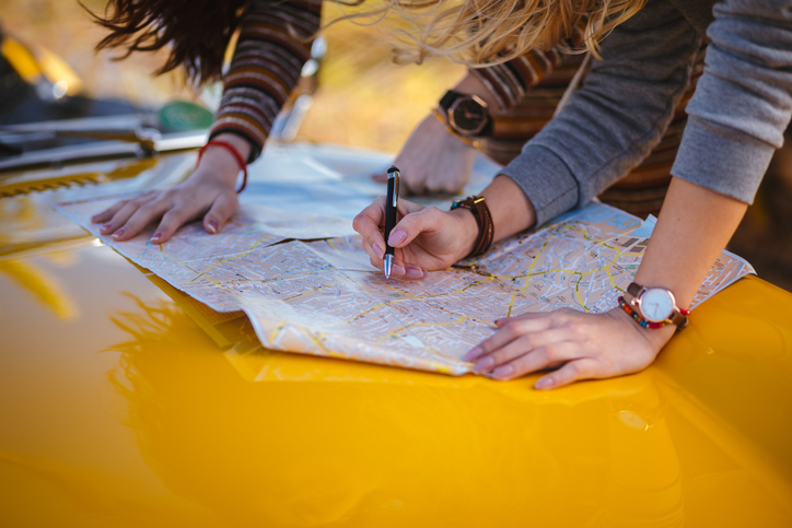 Women on road trip reading map